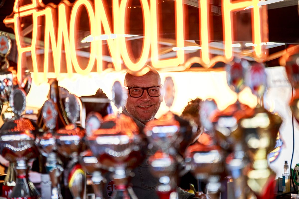 Daniel Nonnenmann hinter Monolith-Leuchtschrift und Pokalen