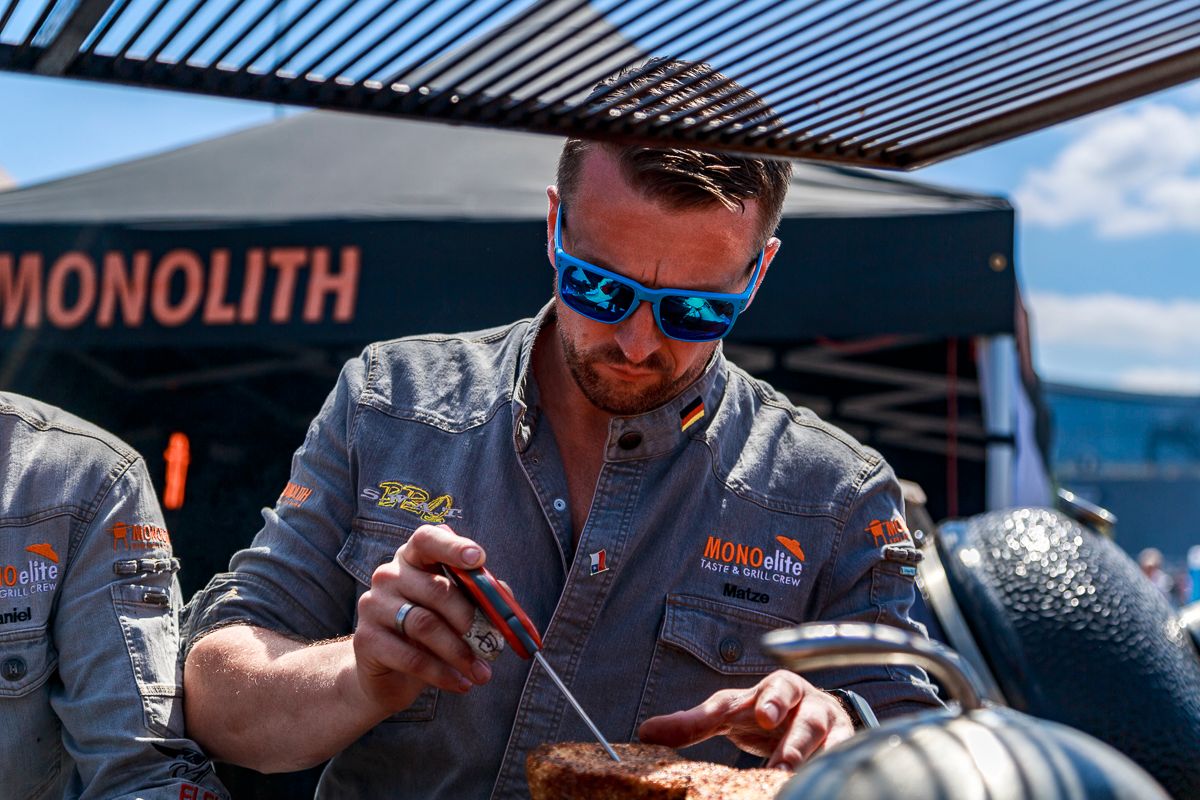 MONOelite Teammitglied schneidet Fleisch am Monolith Grill