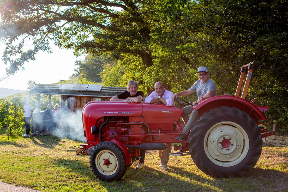 Drei Freunde auf rotem Porsche-Diesel Traktor im Weinberg