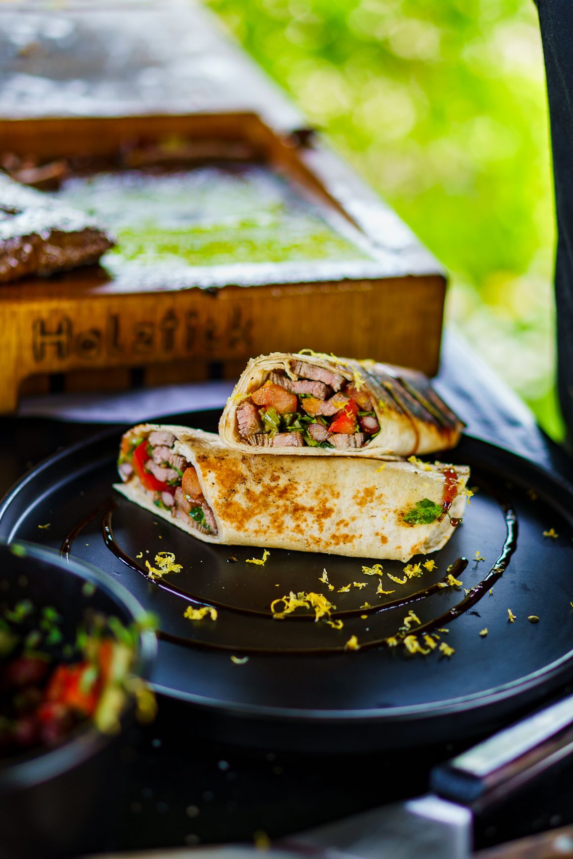 Gefüllte Wraps mit Zitronenzeste auf schwarzem Teller