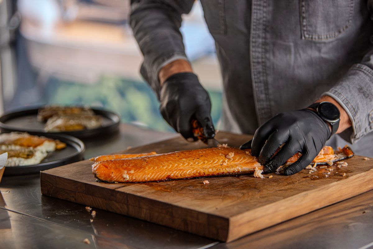 Geräucherter Lachs wird auf dem Brett filetiert