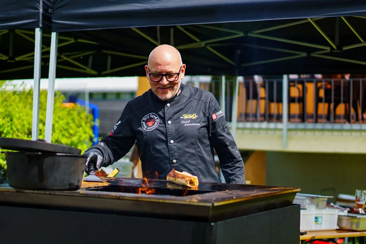 Daniel Nonnenmann bereitet Essen an einer Grillplatte über offenem Feuer zu